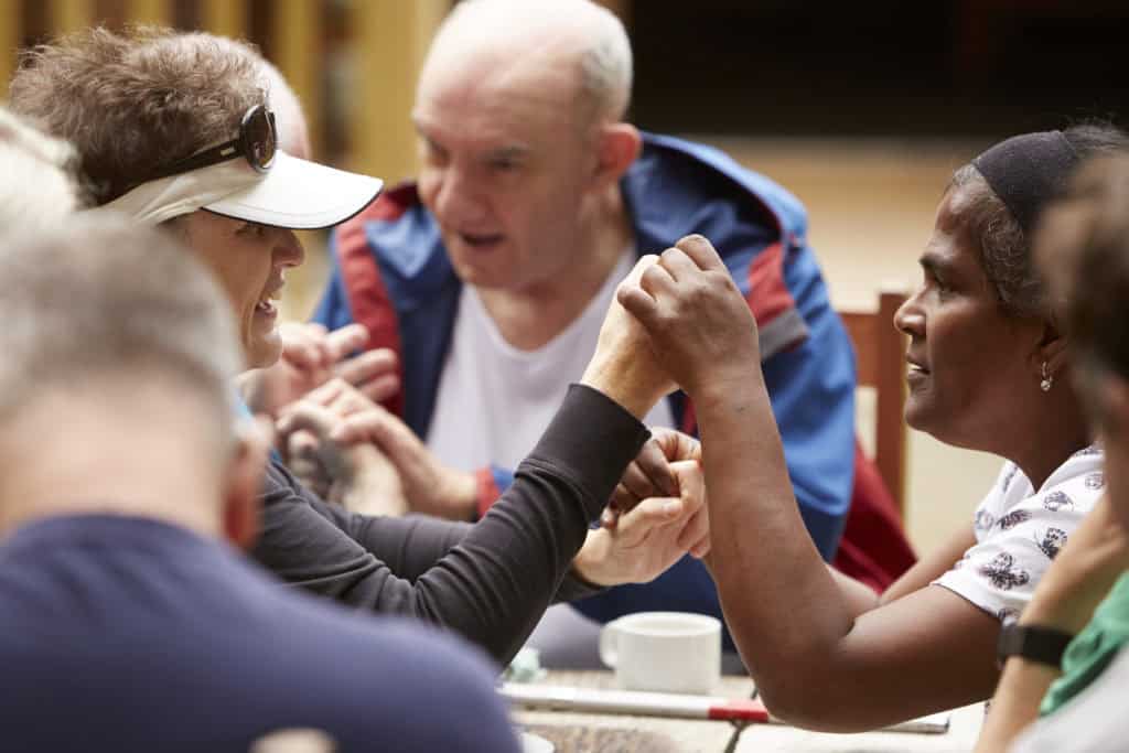 A group of people talking using hand-under-hand signing.
