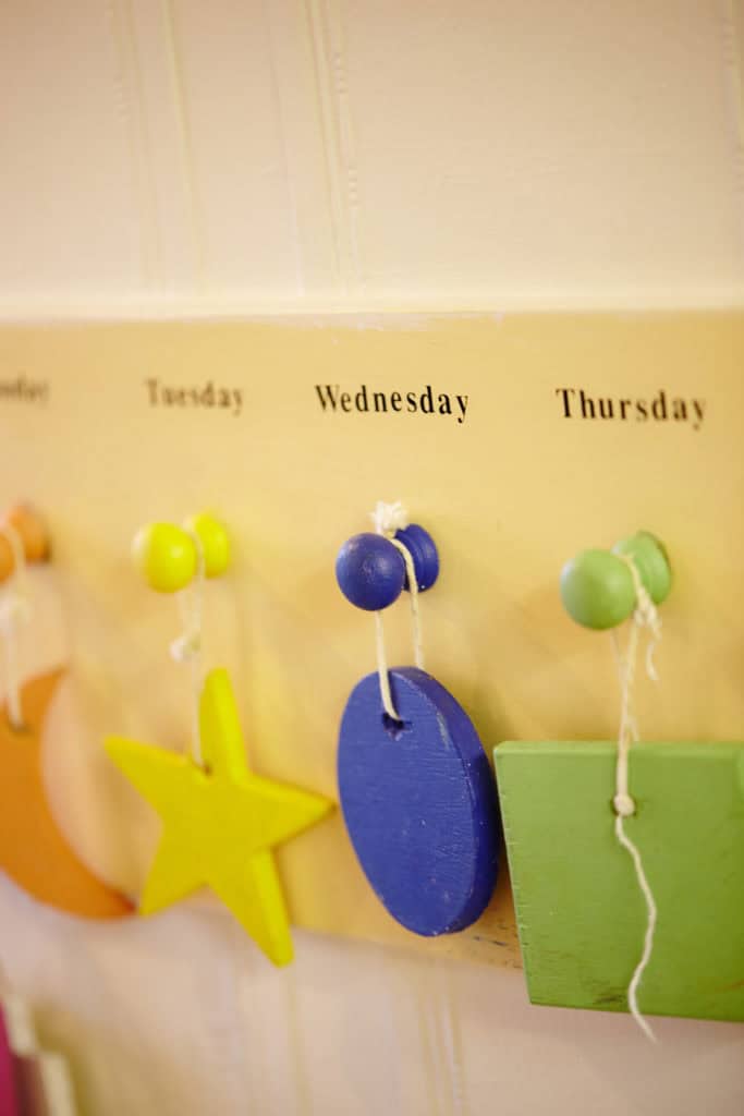 A hanging yellow star, blue circle and green square on pegs above which say the days of the week