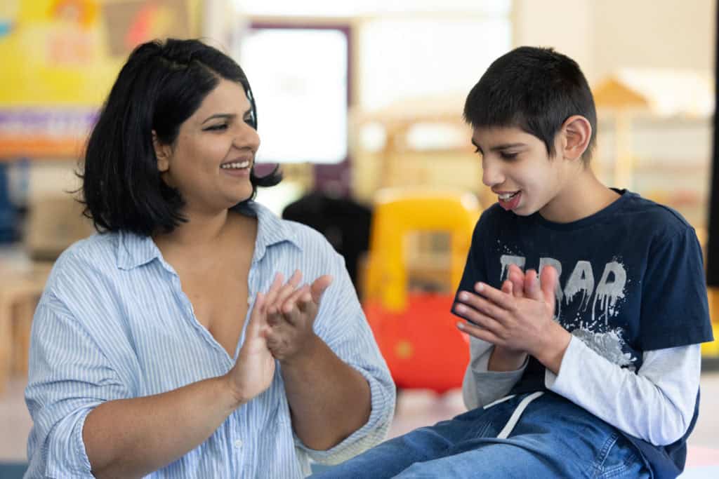 Nakita and Nayan smiling and signing together at Sense Family Centre in Kingswood, Bristol.