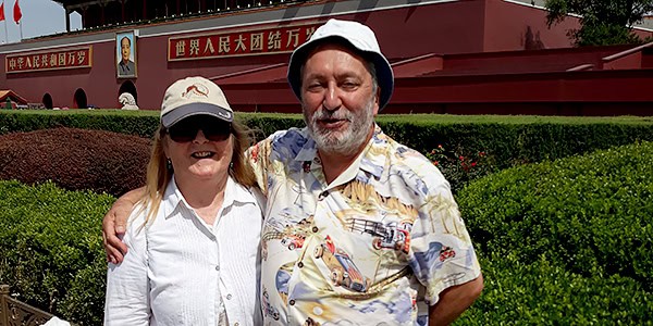 A man and a woman standing outside with their arms around each other. / --