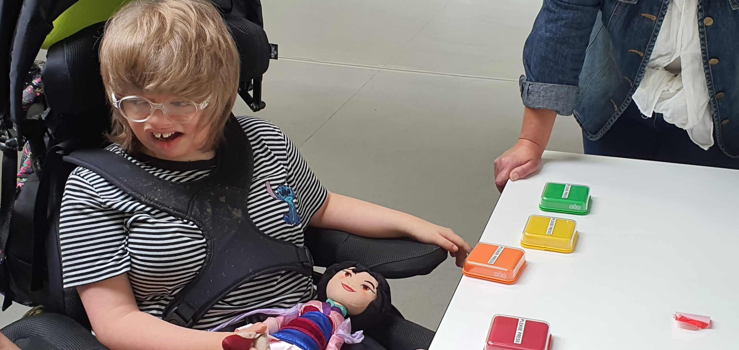A young woman in a wheelchair sat at a table with audio buttons
