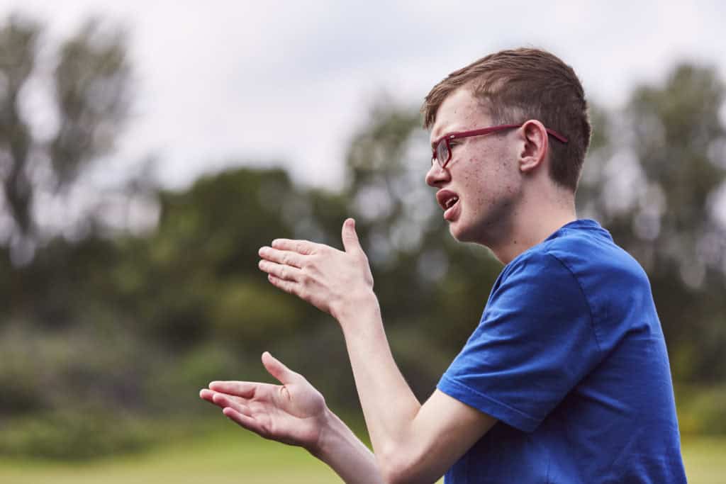 George, a young man wearing glasses, using BSL to communicate.