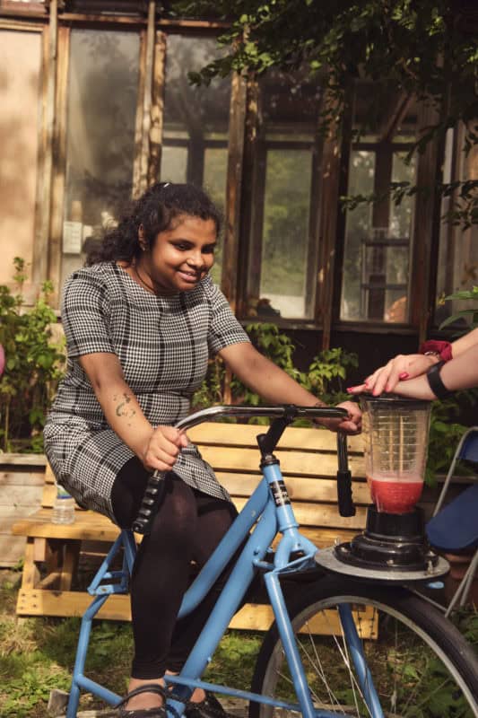 A woman rides a bike that powers a smoothie blender