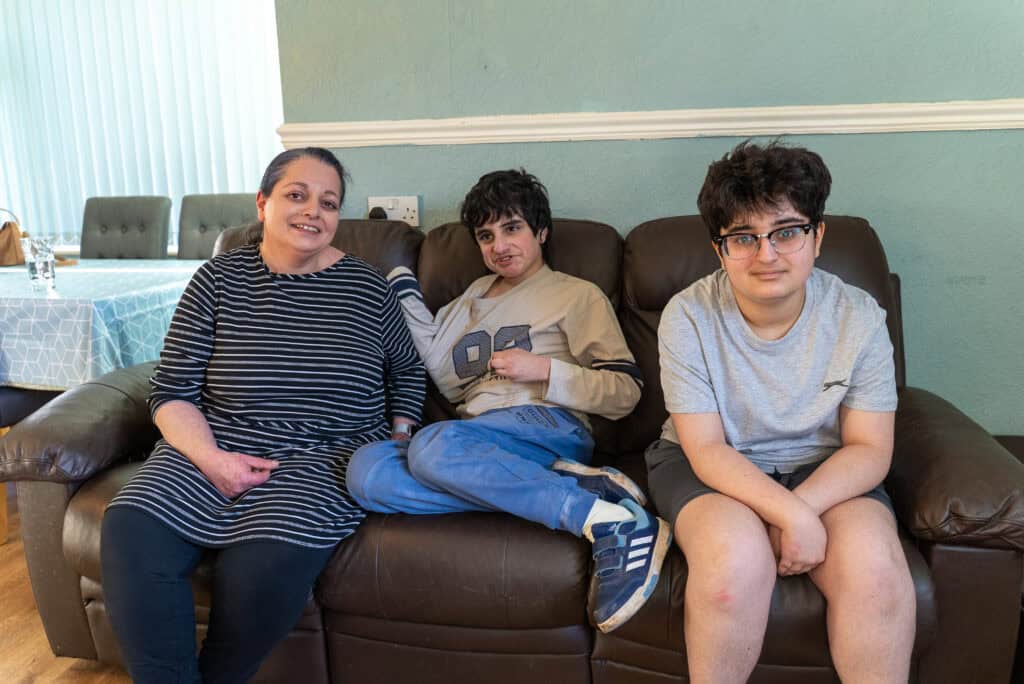 Pictured (left to right): Sandra, Ayman and Caroline are sitting on a brown leather sofa. Sandra and Caroline look to the camera, Ayman is looking off to the left