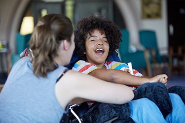 A woman supporting a young person in a wheelchair