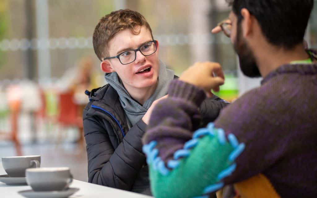 George and Shaanvir chatting over a cup of tea using British Sign Language.
