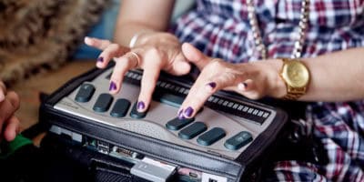 Close-up of hands using a braille machine.