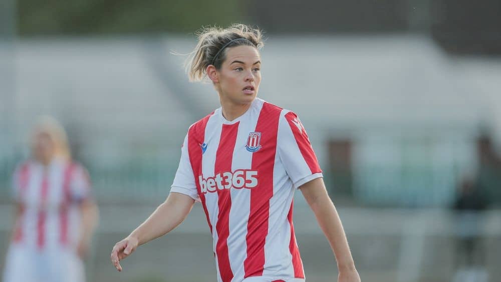 Callan wearing a football top looks to her left