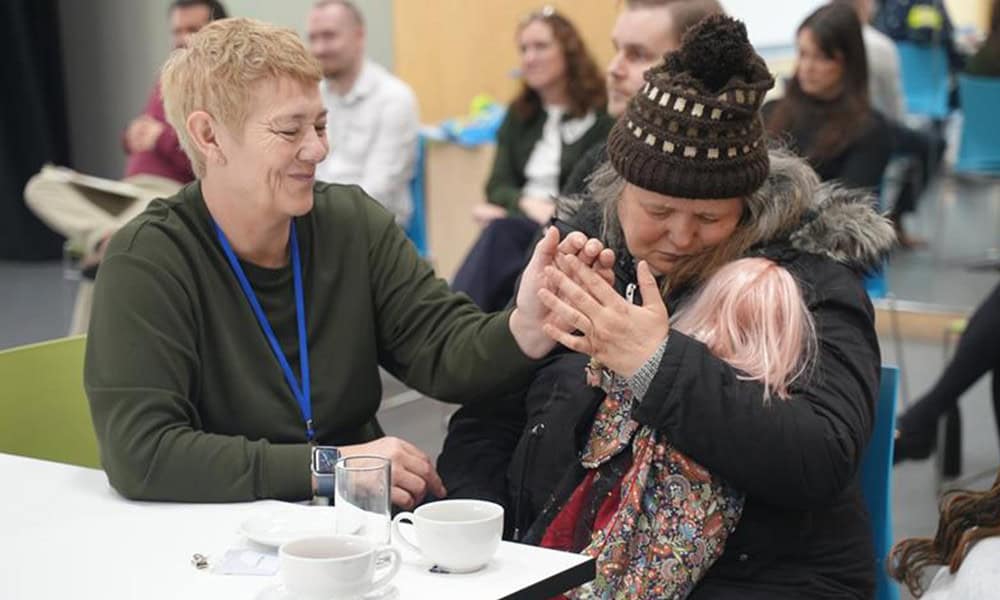 Helene Ryles (right), a deafblind woman, advocate and artist, who is being supported to communicate her experiences of social care to civil servants through deafblind sign language.