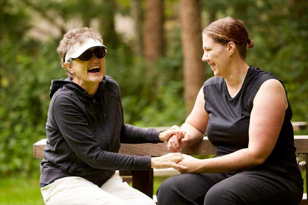 Catherine and Sarah sitting on a bench laughing on a Sense holiday
