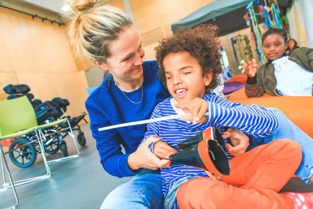 A young boy with curly hair being supported by a support work at Sense TouchBase Pears.