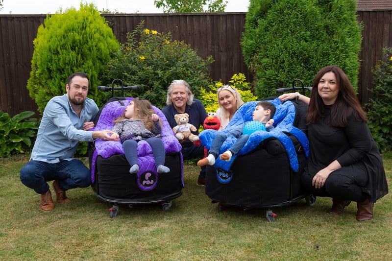 The Clucas parents crouch either side of their two children in the garden, with Rob Lloyd and a woman in the middle holding teddies.