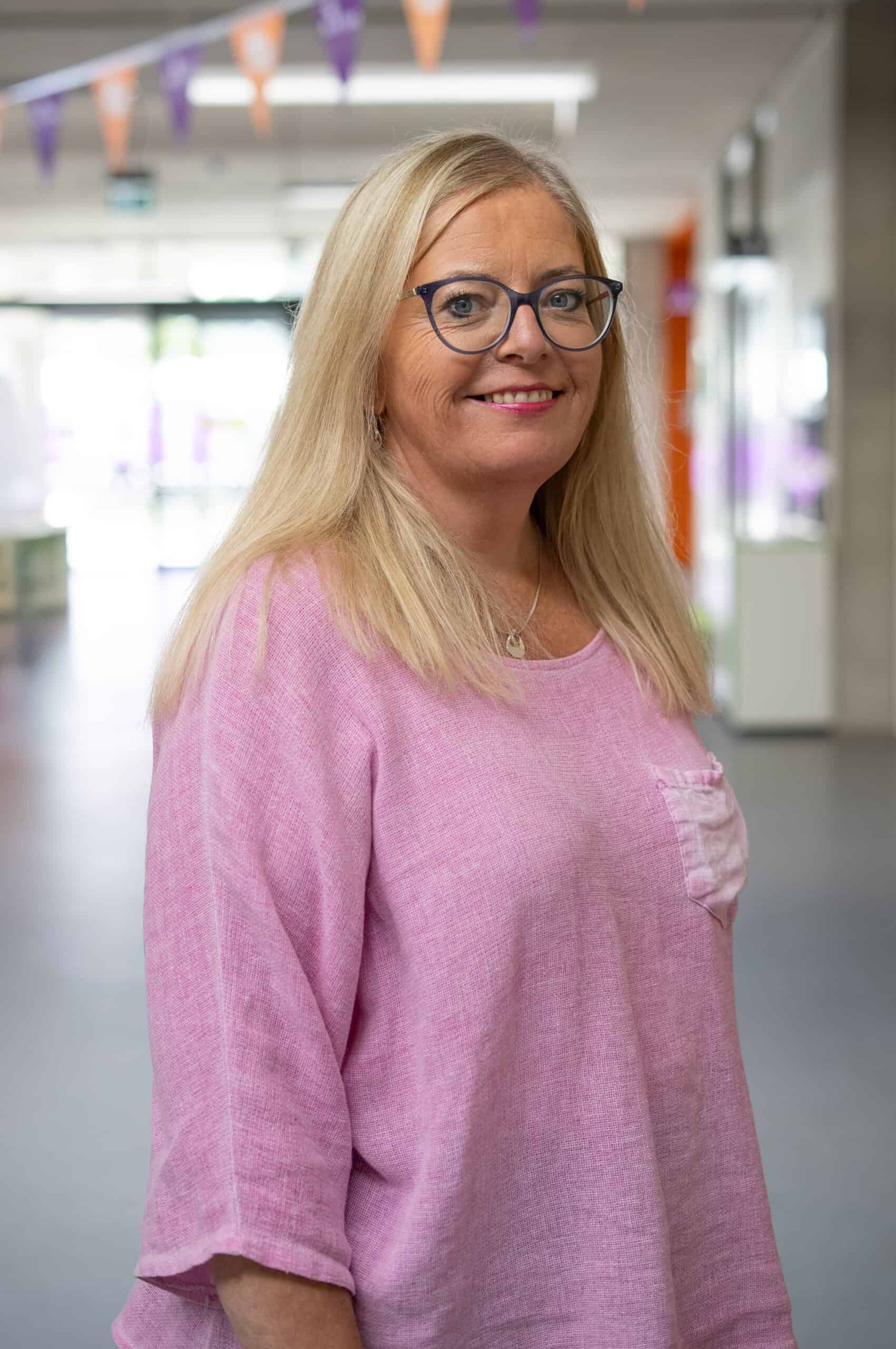 A portrait of a woman wearing a pink shirt.