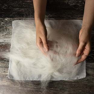 A hand pressing the wool into the mesh