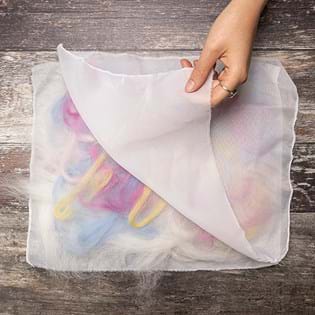 A hand lifting up the top layer of mesh to show underneath