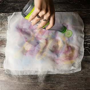 A hand holding a bottle of washing up liquid about the mesh