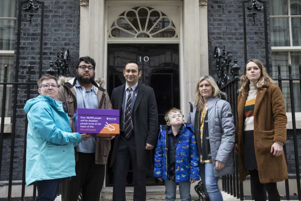 6 people stand in front of 10 downing st with a box of petitions