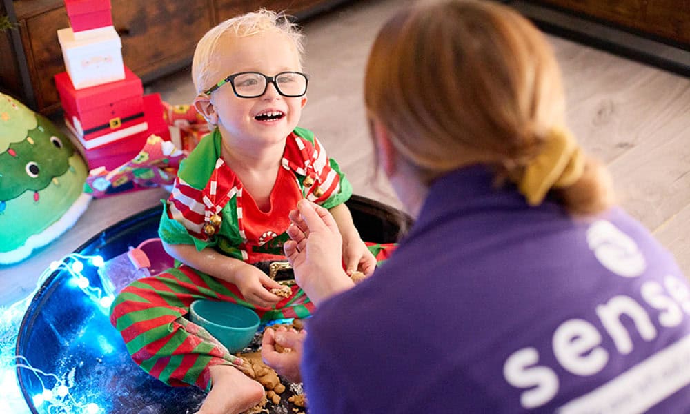 Harvey is a blond-haired boy wearing a Christmas elf outfit and smiling