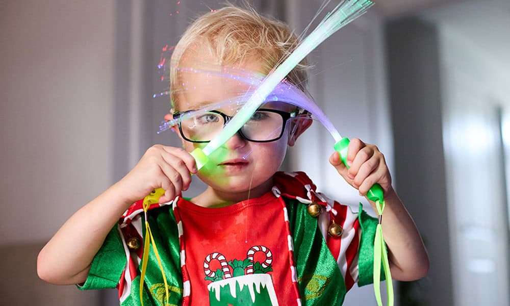 Harvey holds a green and purple sensory light toy up to his eyes