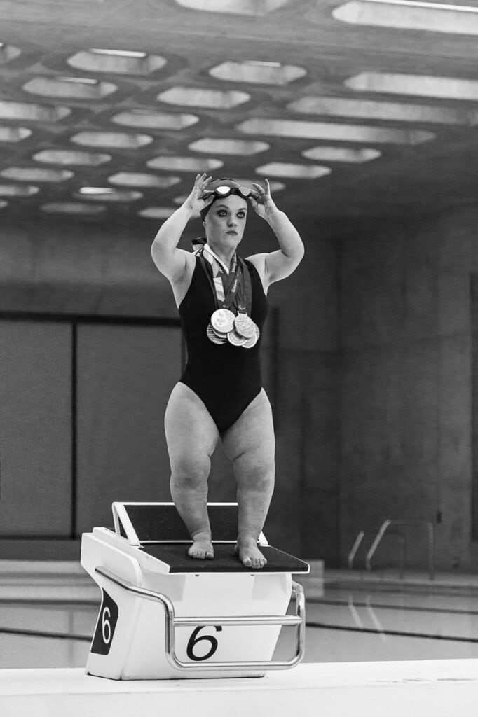 Swimmer Ellie Simmonds standing on a starting block, wearing her medals. Photo by Ian Treherne.