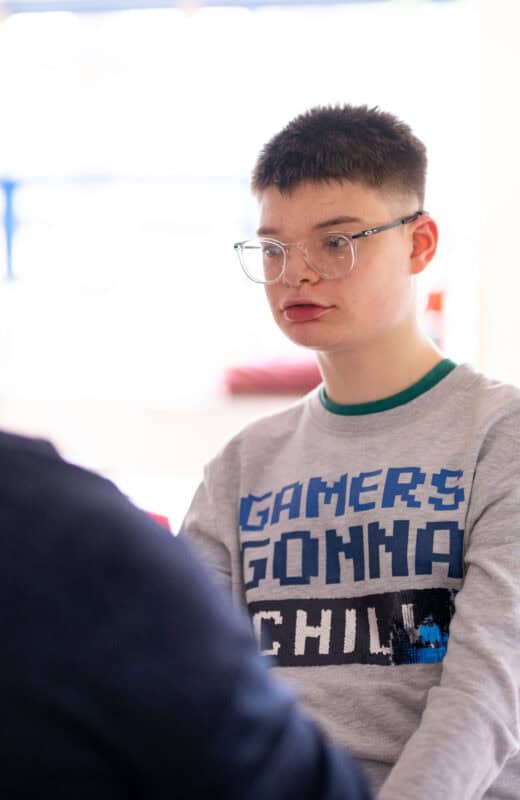 A young man with glasses sits quietly.