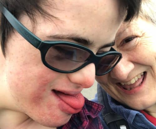 A young man with glasses on looks towards an older woman and they're both having fun.