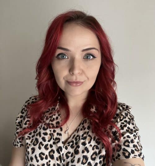 A portrait of a woman with red hear wearing a leopard print top