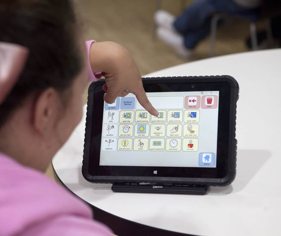 Maria is pointing at the screen of a tablet, which has several symboles including a clock, a sun and a window showing night time