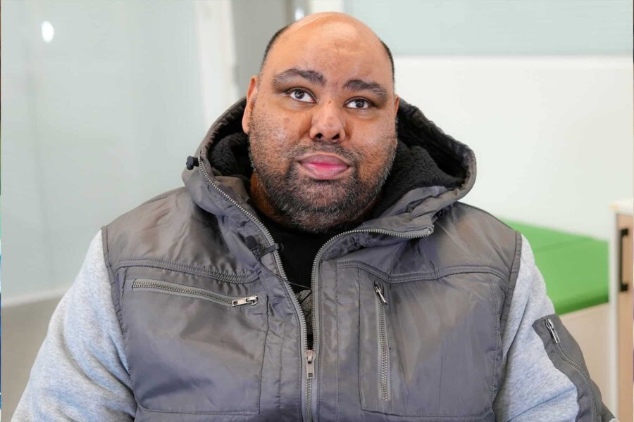 Mo Azeem, a man sitting down wearing a grey bodywarmer and looking straight at the camera