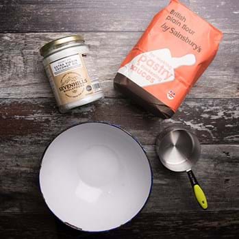 Coconut oil, a measuring spoon, flour in a red packet and an empty bowl