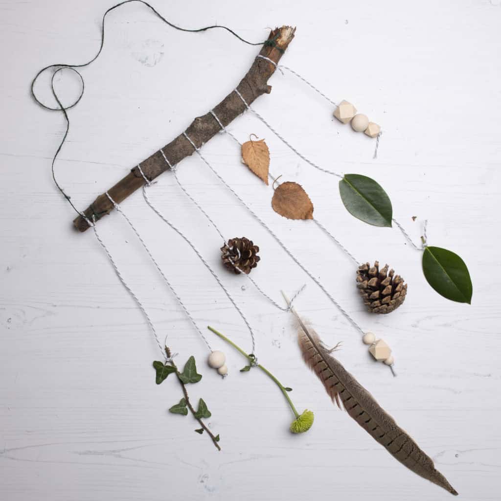 A hanging mobile with natural items like leaves and feathers