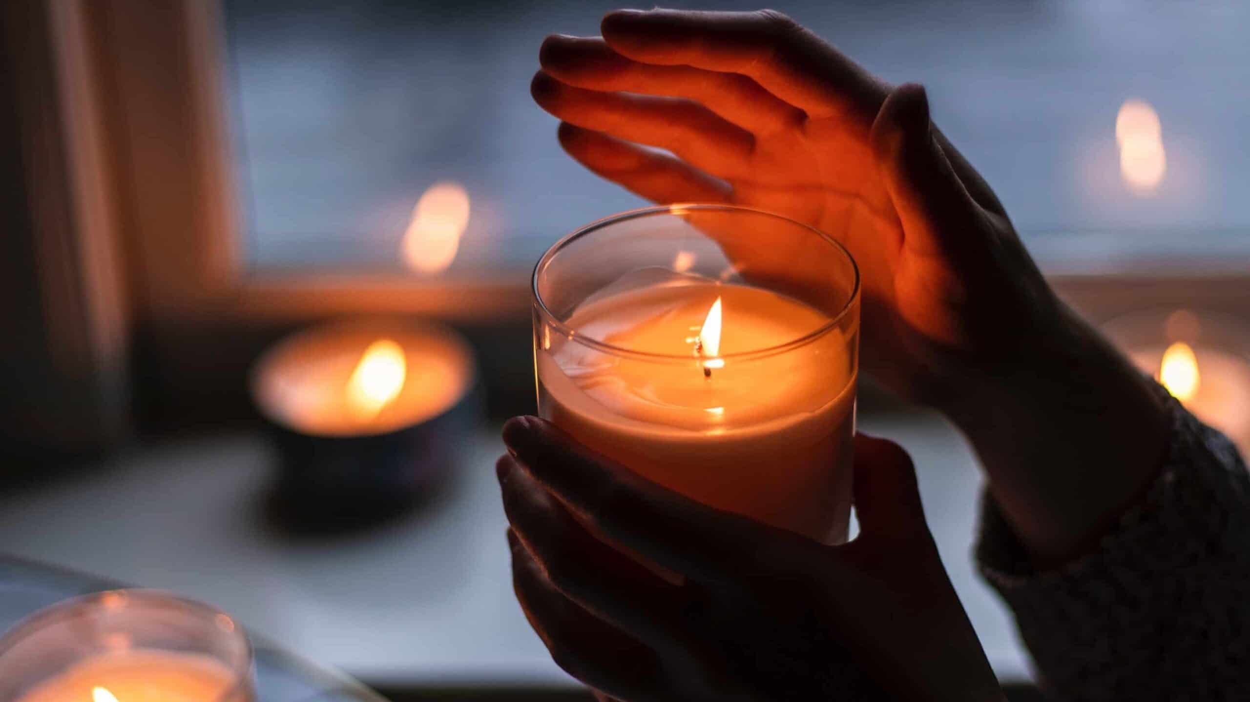 Hands holding a candle, surrounded by other candles.