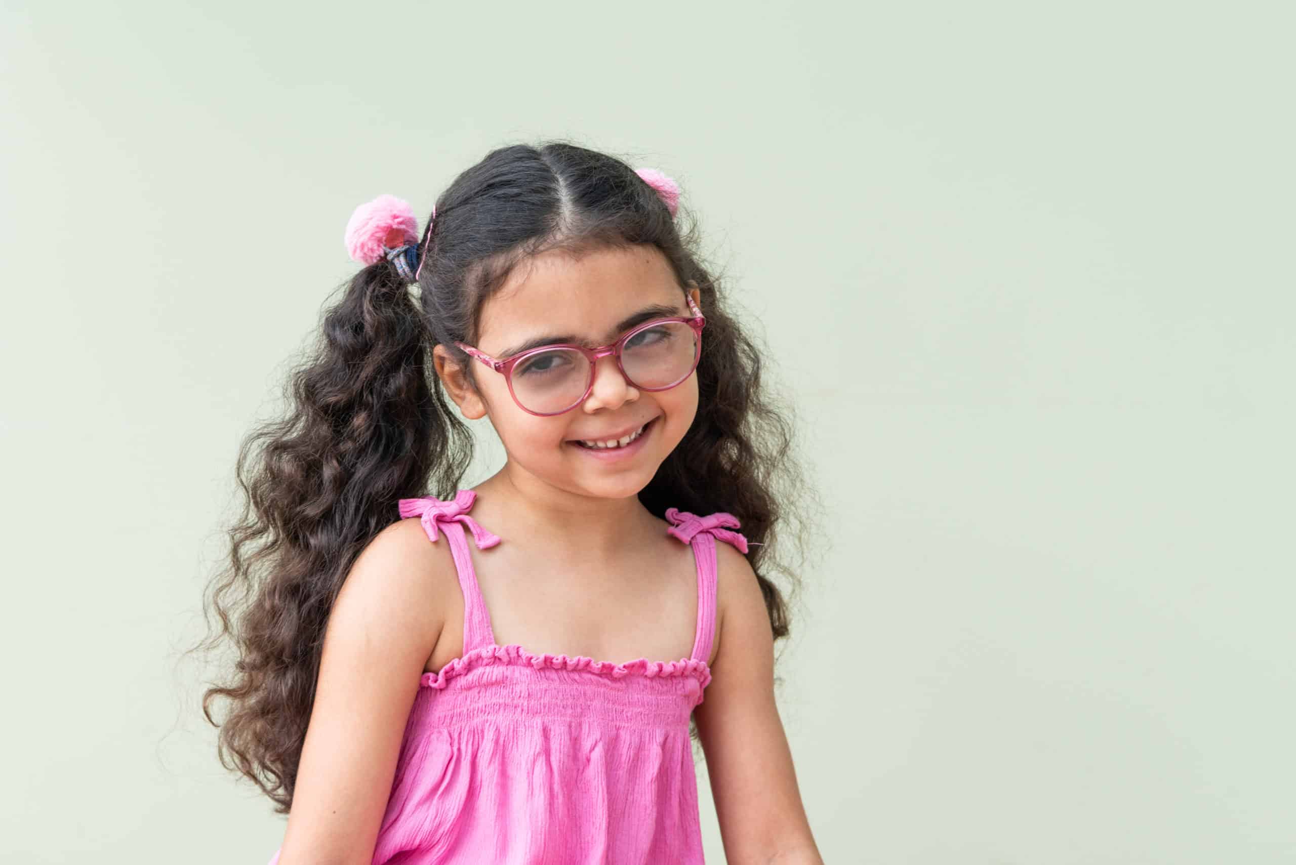 Remi, a young girl with long pigtails and glasses, smiling at the camera.
