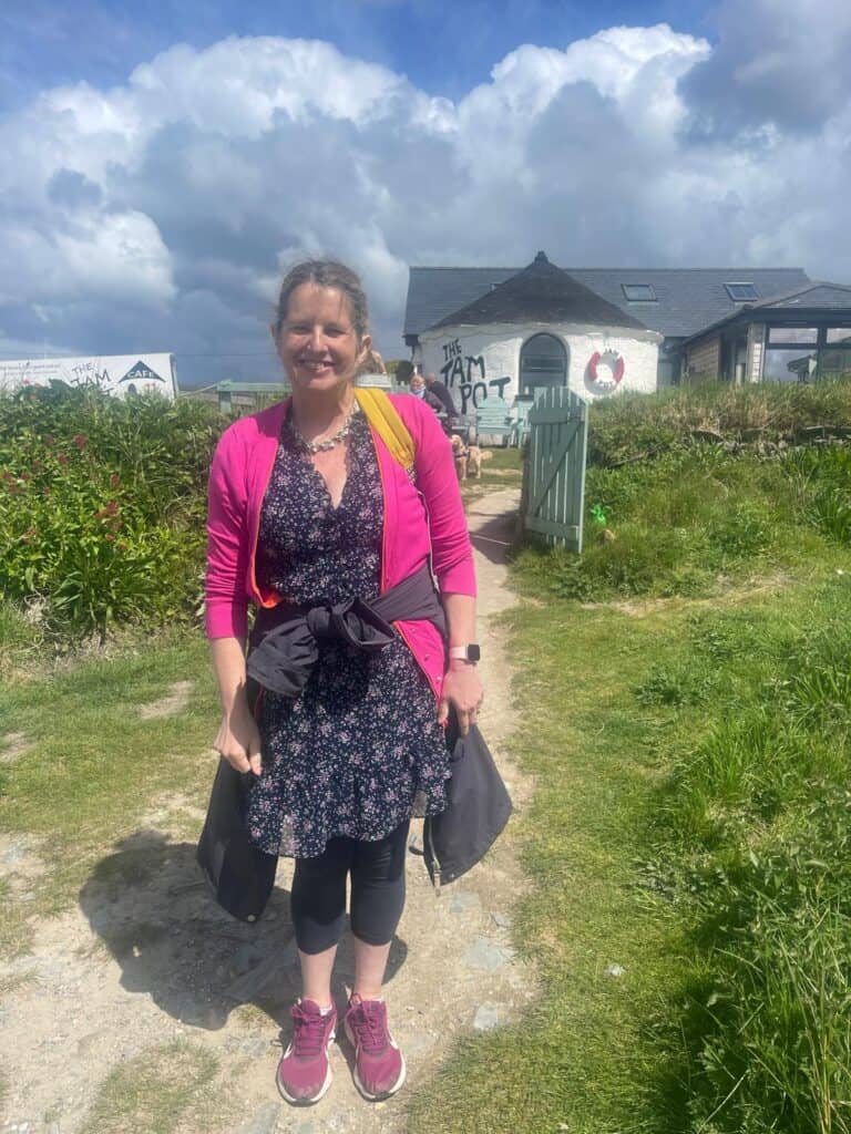 A woman standing outside in nature, looking happy in front of a café.