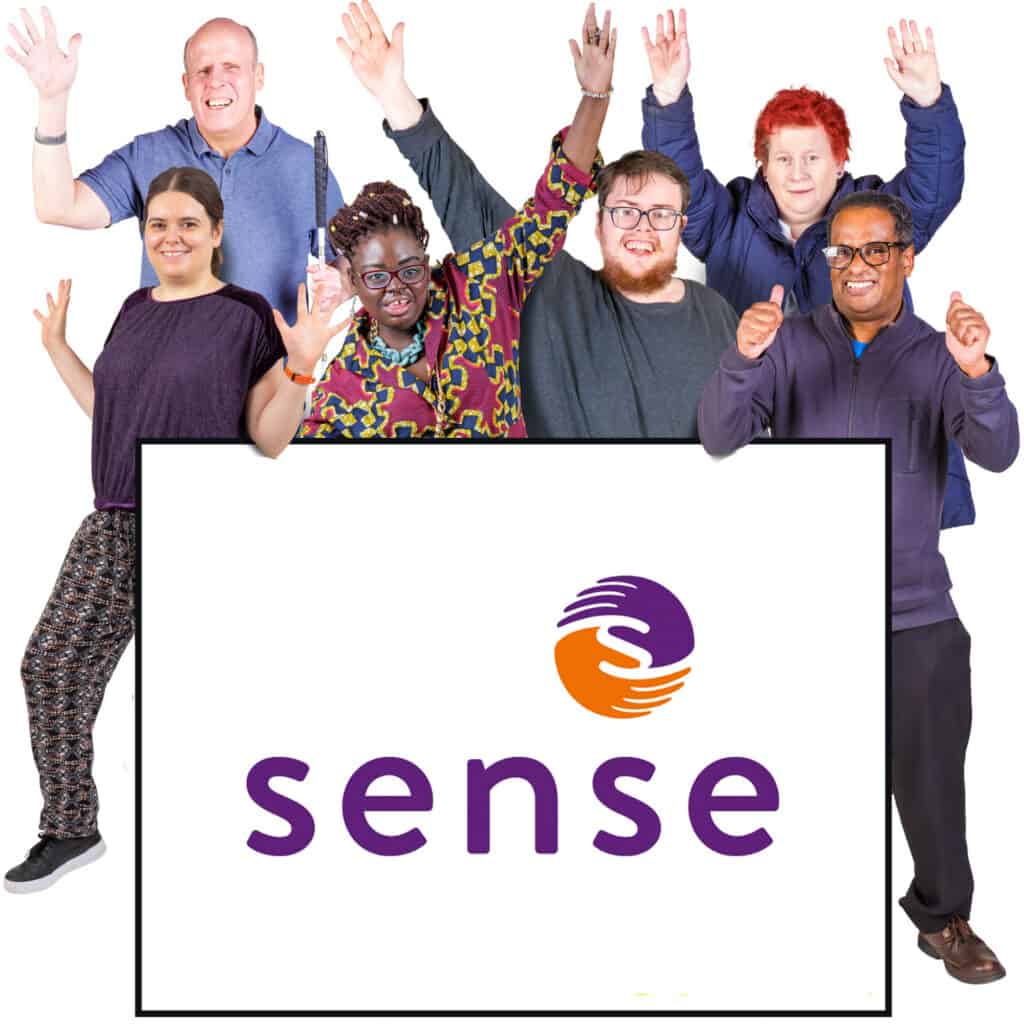 A group of people cheer behind a sign saying 'Sense'