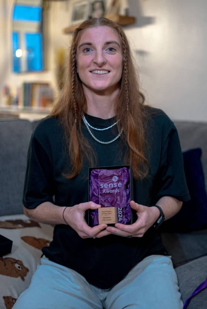 Elle is a smiling young woman holding her Sense Award.