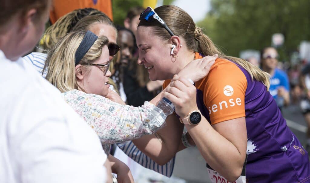 A sense runner and her sister share a cuddle on the side of the track.
