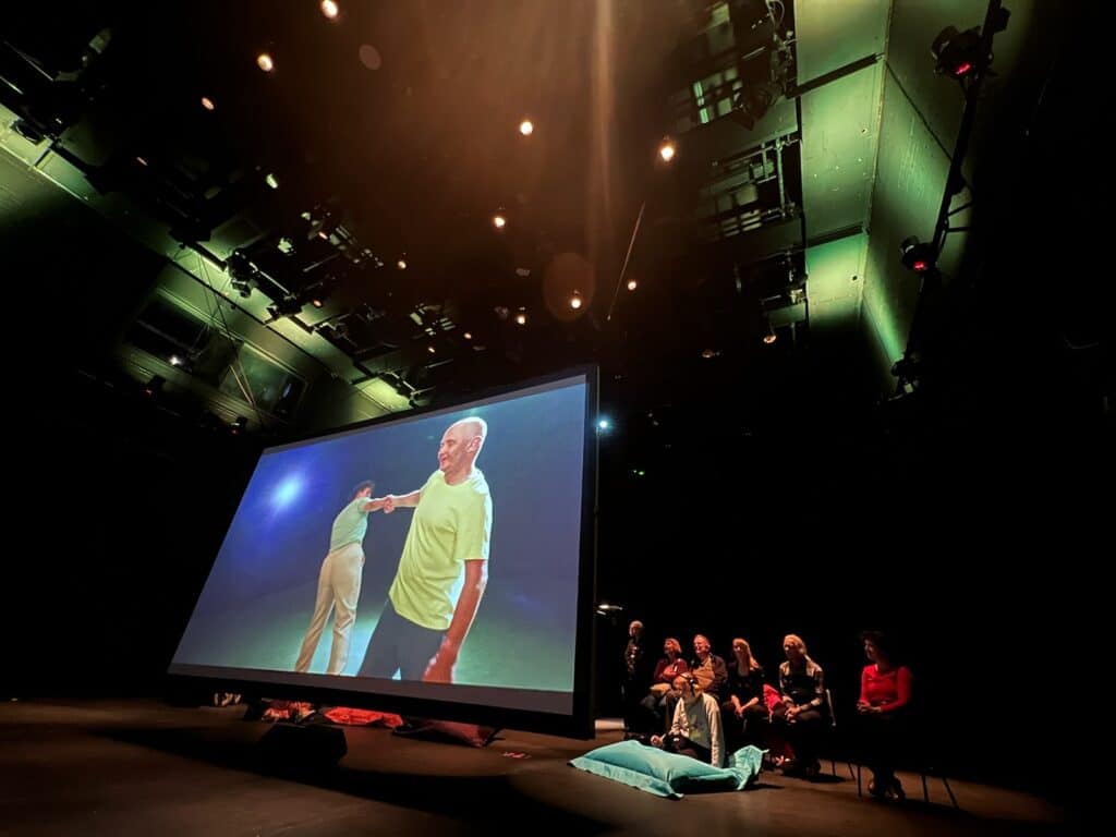 A fim showing on a large screen to an audience in a darkened theatre