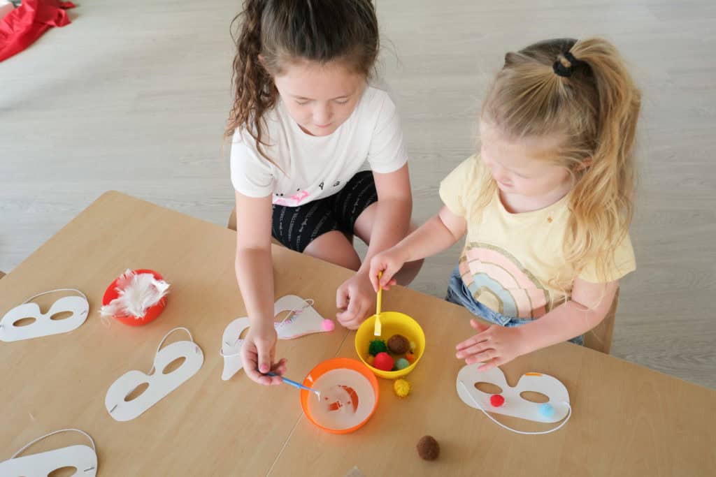 two young children are painting on a table while stiting down