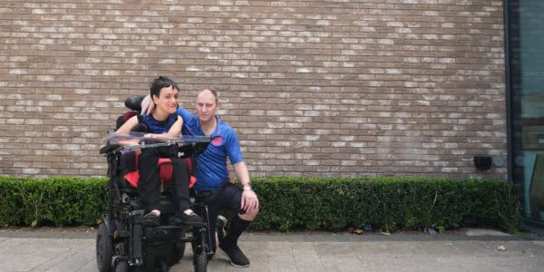 a man is kneeling next to a woman in a wheelchair on the pavement