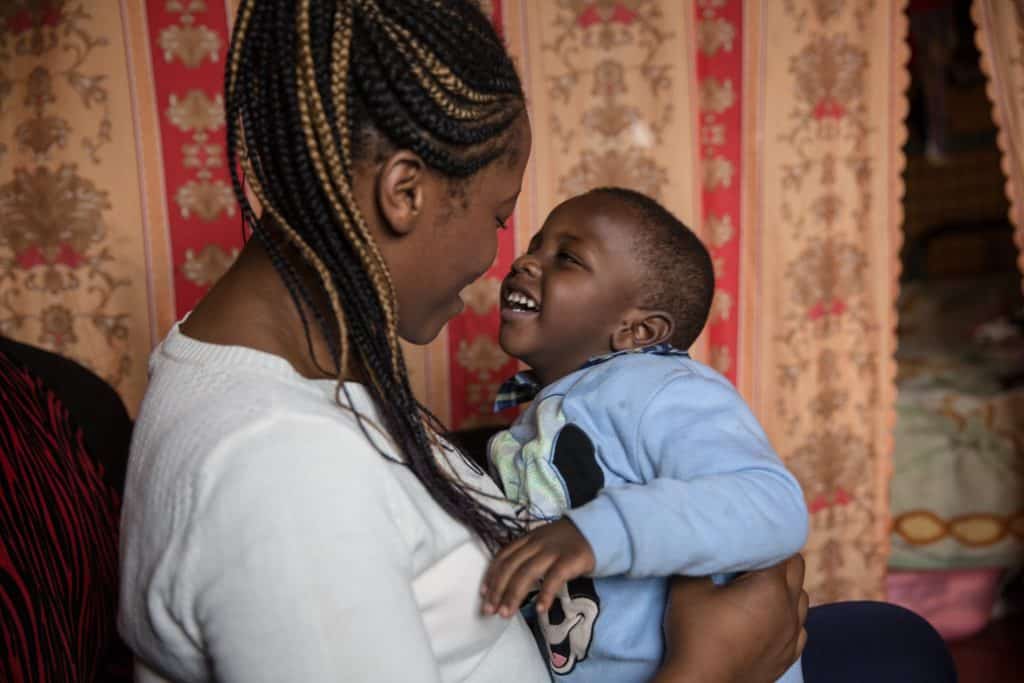 A woman holds a smiling boy