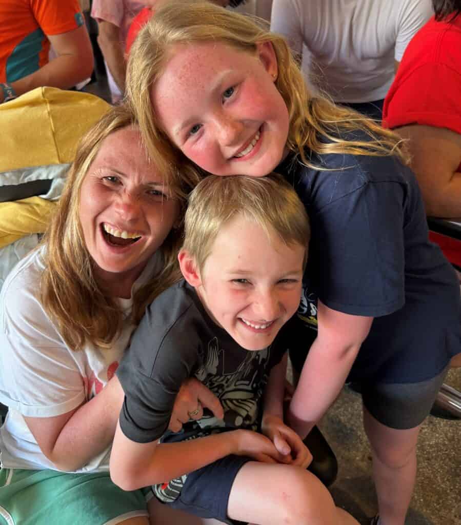 Steph is sat with her son on her lap, and her daughter with her arm around her back. They are all smiling widely and touching heads for the photo.