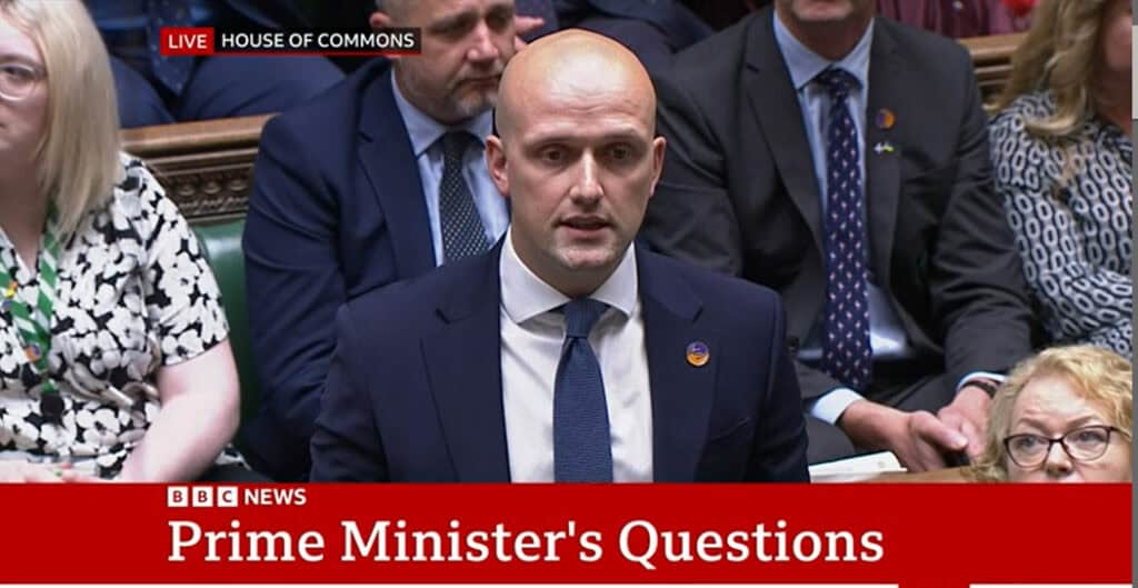 Screenshot of Stephen Flynn MP wearing a Sense badge in parliament. There is a caption from BBC news that says 'Prime Minister's questions'
