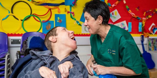 A man in a wheelchair and a woman smiling at each other.