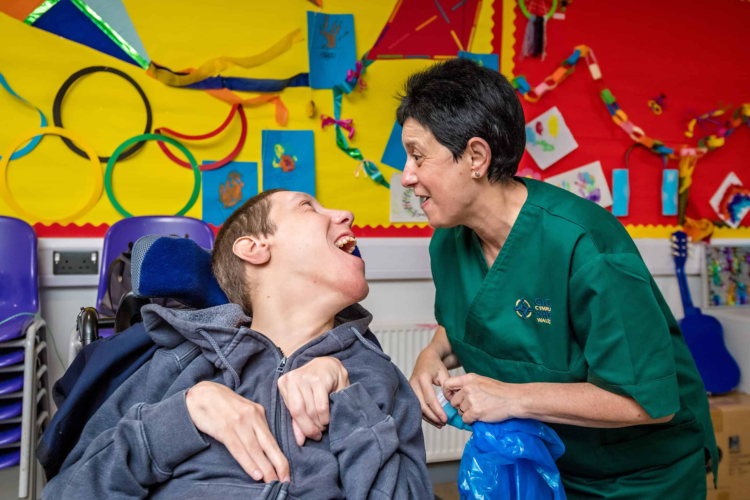 A man in a wheelchair and a woman smiling at each other.